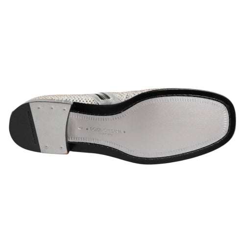 A single Dolce & Gabbana shoe shown from the sole view, featuring a silver metallic perforated leather upper, a black outsole, and a silver metal heel cap on a white background.