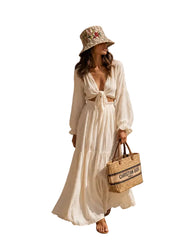 Woman in a white dress and hat standing by a dock with boats in the background