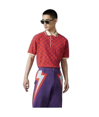 A model wearing a red short-sleeve knit top with a white graphic print and purple skirt, set against a plain light gray background.
