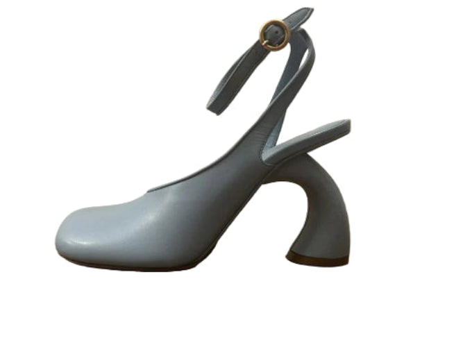 Light blue high-heeled shoe on a wooden floor with a beige wall background