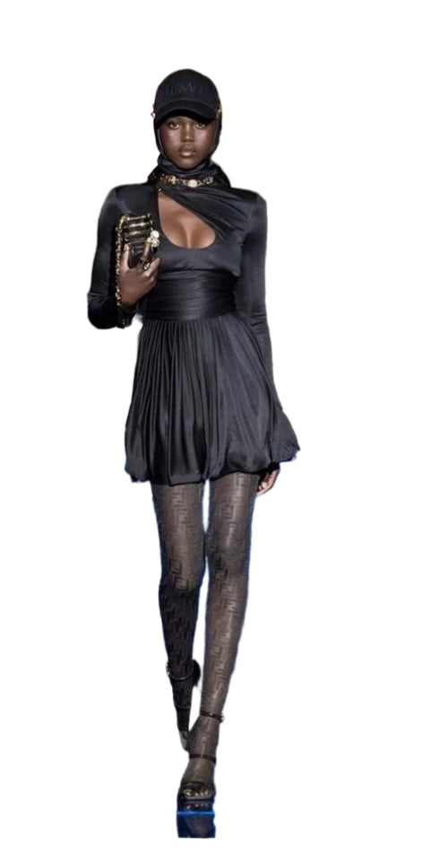 Person wearing a black outfit with a hood and pleated skirt on a white background