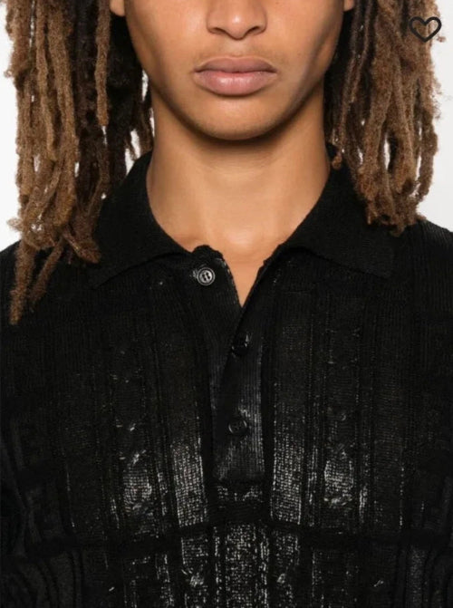 Person wearing a black textured shirt with a plain background