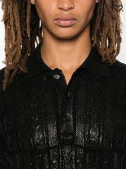 Person wearing a black textured shirt with a plain background