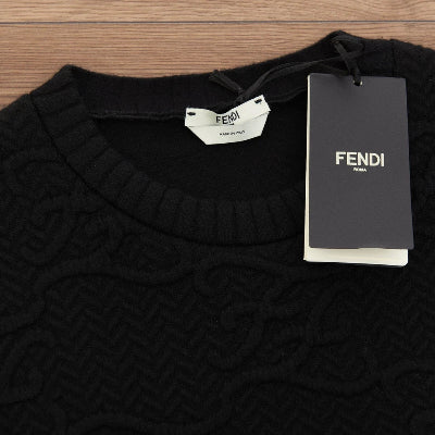 Black sweater with Fendi label and tag on a wooden surface