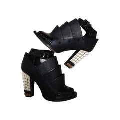 Black high-heeled shoes with decorative elements on a white background