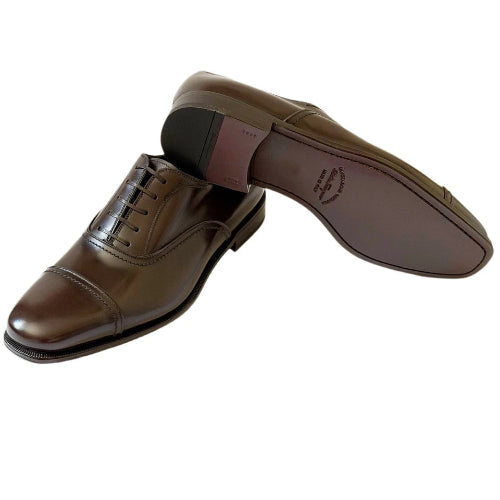 A pair of men's brown leather oxford shoes, with one shoe standing upright to show the brown leather upper and the other lying on its side to display the brown outsole.