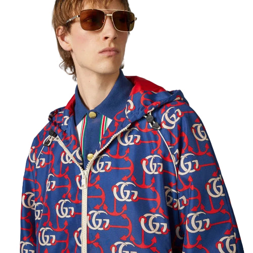 Person wearing a colorful jacket with a pattern of letters and numbers, standing against a neutral background.