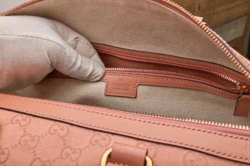 Close-up of a Gucci handbag with a gloved hand opening it.