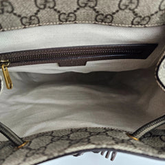 Close-up of a Gucci handbag with monogram pattern and gold zipper.