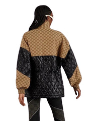 Person wearing a patterned jacket with a geometric design on a plain background