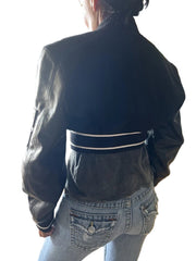 Person wearing a dark jacket and light blue jeans in an indoor setting