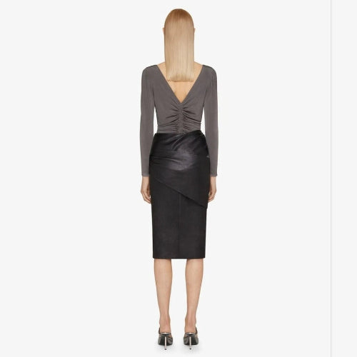 Woman wearing a gray long-sleeve top and black leather skirt on a white background