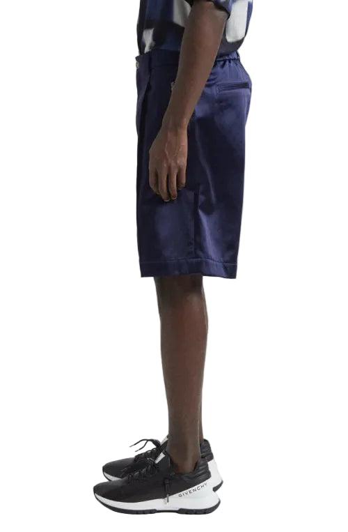 Person wearing navy shorts and black sneakers on a white background