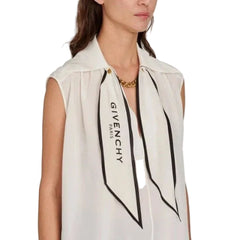 Woman wearing a sleeveless top with a visible brand logo on a plain background