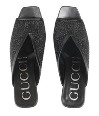 Black studded high-heeled shoes with Gucci logo on a white background