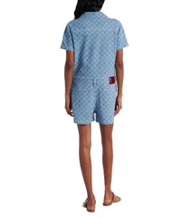 Person wearing a blue patterned dress with a red tag on a white background