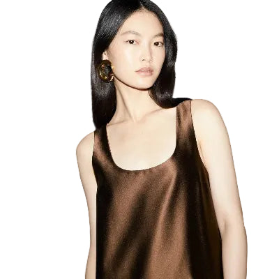 Woman wearing a brown satin dress against a plain background