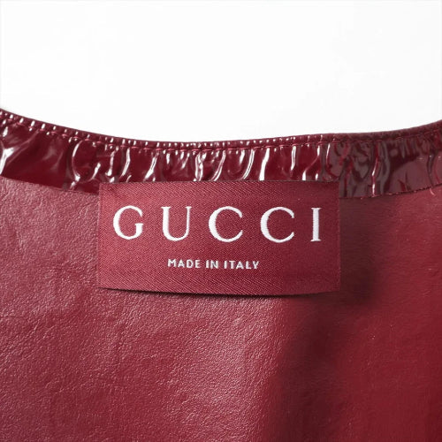 Close-up of a burgundy leather Gucci garment showing the interior waistband with a glossy patent leather trim and a central fabric label reading 'GUCCI MADE IN ITALY'.