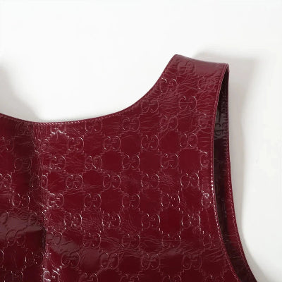 Close-up of a glossy burgundy patent leather shoulder bag featuring an embossed interlocking GG monogram pattern, set against a plain white background.