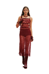 Woman wearing a red lace outfit in a reflective, orange-lit room.