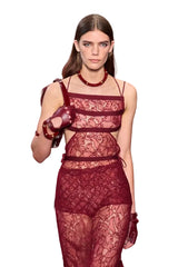 Model wearing a red lace outfit on a runway
