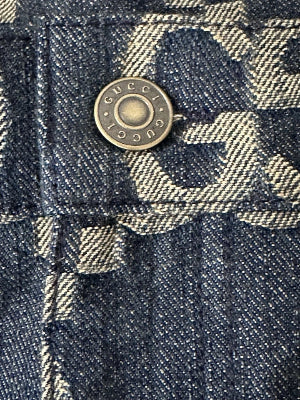 Close-up of a denim button with 'Gucci' branding on a checkered fabric background.