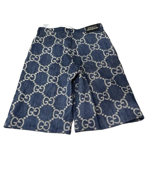 Blue denim shorts with Gucci logo pattern on a wooden surface