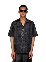 Man wearing a black patterned shirt with animal designs on a white background