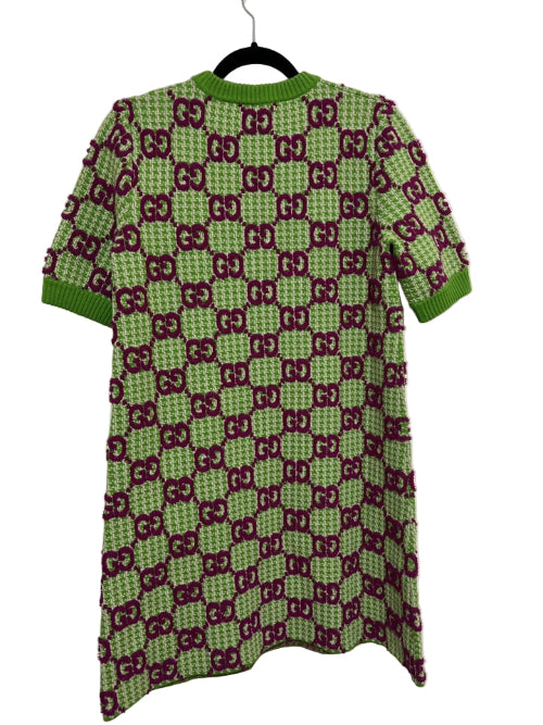 Green and red patterned dress on a hanger against a white background