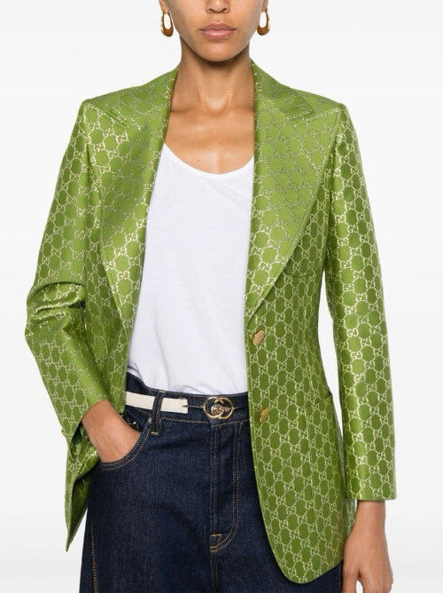 Person wearing a green patterned blazer over a white top and blue jeans on a white background