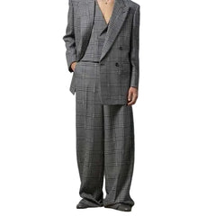 Person wearing a gray plaid suit against a plain background