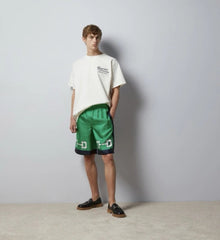 Person wearing a white t-shirt and green shorts against a plain background