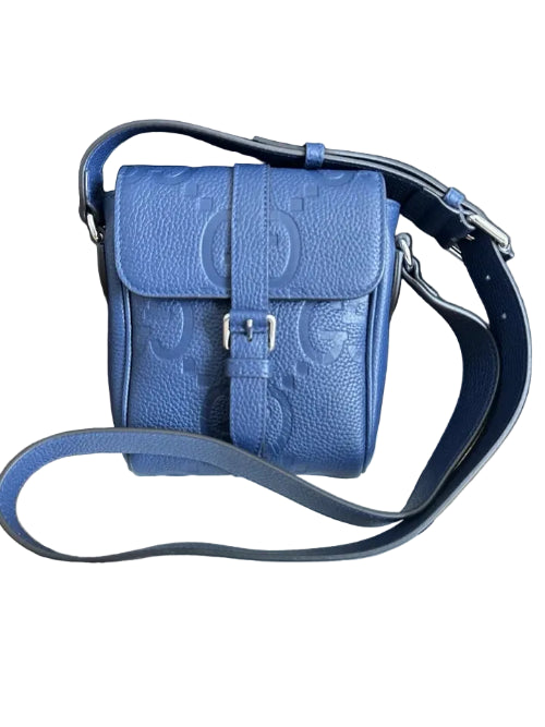 Blue Gucci bag on a wooden surface with Gucci packaging underneath