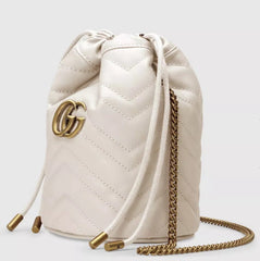 White quilted drawstring bag with gold chain and logo on a white background