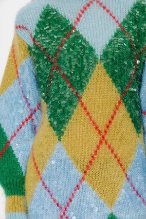 Close-up of a knitted fabric with argyle pattern featuring green, yellow, and red colors.