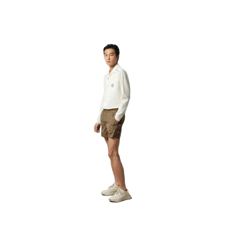 Person wearing a white shirt and brown shorts standing against a plain gray background