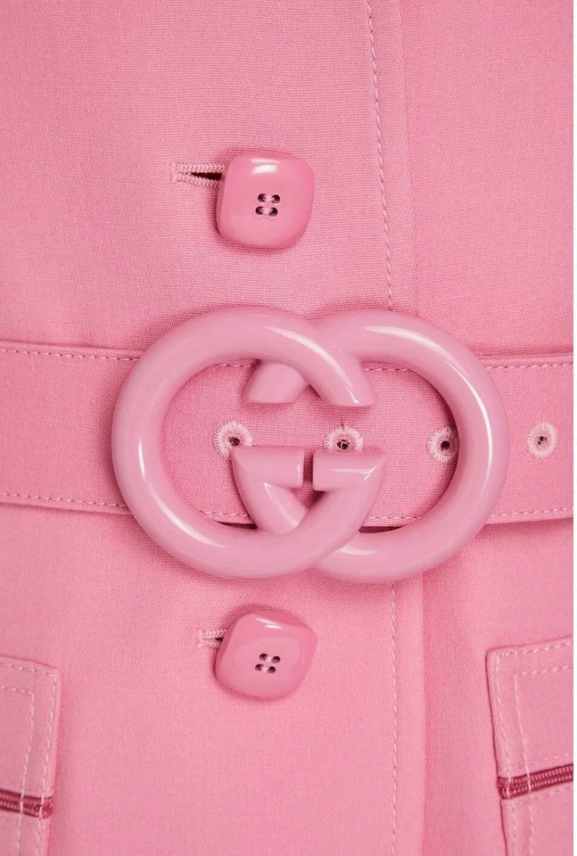 Close-up of a pink coat with a large circular button and two smaller buttons on a matching pink background.