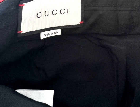 Close-up of the interior waistband of a black Gucci garment, showing the white Gucci brand label stitched onto the inside of the waistband.