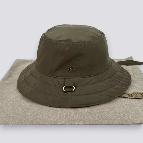 Brown bucket hat with a logo on a beige surface