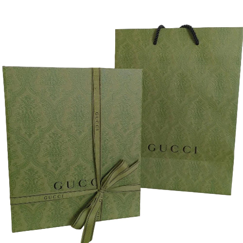Two green Gucci gift bags with ribbons on a white background