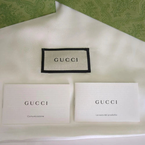 Gucci branded items including a patch, cards, and a box on a green patterned background