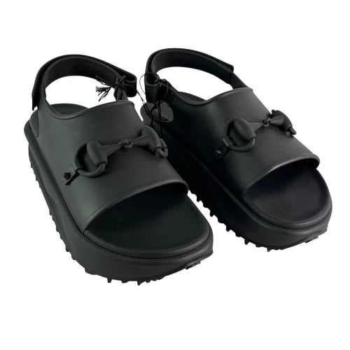 Pair of black sandals with bow details on a white background