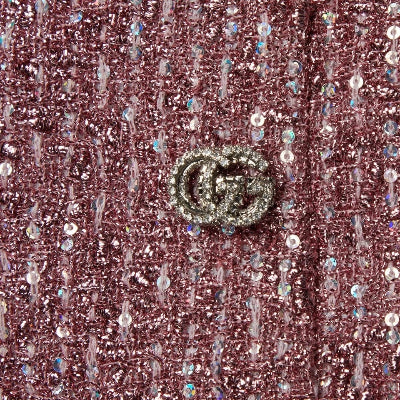 Close-up of a pink glittery fabric with a decorative button featuring a logo.