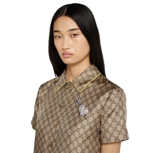 Model wearing a patterned shirt with a brooch on a white background