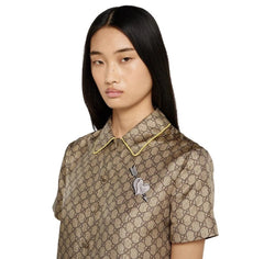 Model wearing a patterned shirt with a brooch on a white background