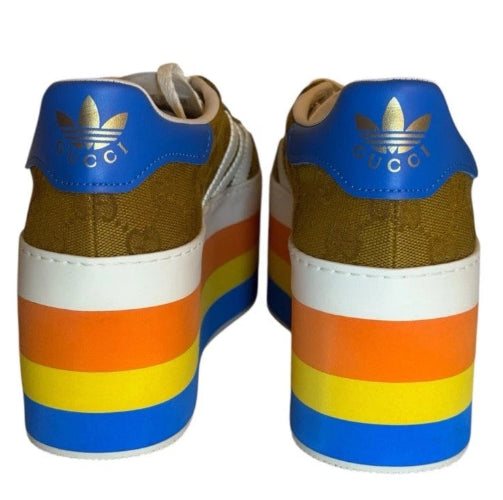 A pair of low-top sneakers shown from the back, featuring a multicolor design with blue, gold, brown, orange, yellow, and white stripes on the stacked heel and white midsoles.