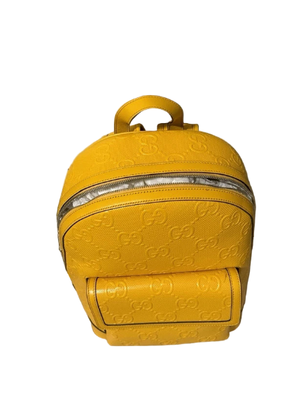 Yellow embossed backpack on a beige surface with a black box in the background