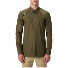 A man wearing an olive green long-sleeve button-up shirt with a collar and a small chest pocket, paired with khaki pants, against a light gray background.