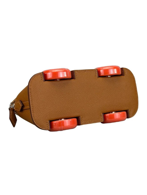 A brown textured leather belt buckle shaped like a skateboard, featuring four bright orange-red wheels on top, shown against a plain white background.