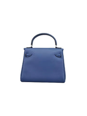 A medium blue leather top-handle handbag with silver-tone hardware, photographed against a neutral light gray studio background.